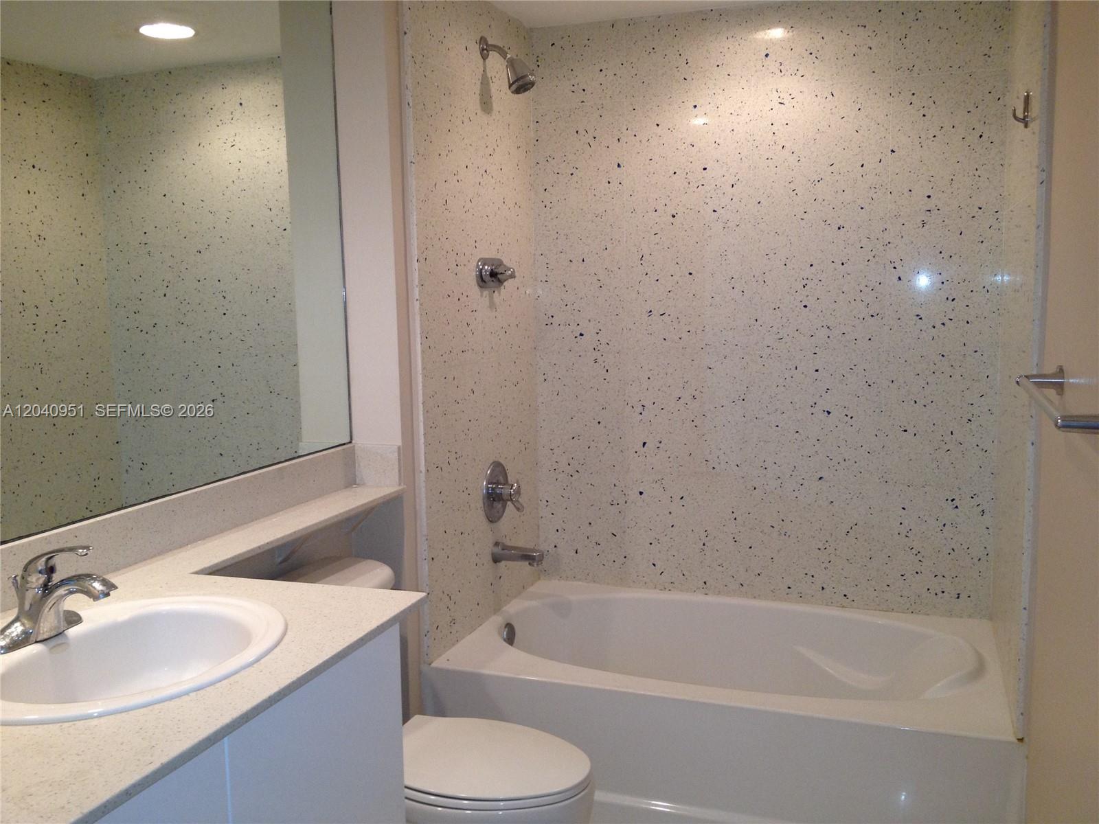 A bathroom features a vanity with a sink, a toilet, and a speckled tub surround — 325 S Biscayne Blvd # 1414, Miami FL 33131, MIAMI, FL
