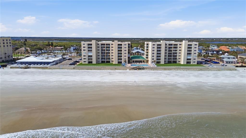 An aerial view shows a multi-story beachfront condominium complex with a pool and parking lot — 4495 S ATLANTIC AVENUE UNIT 501, PONCE INLET, FL