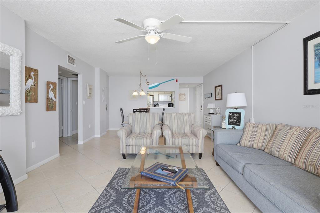 A living room features light tile flooring, a ceiling fan, and a gray sofa — 4495 S ATLANTIC AVENUE UNIT 501, PONCE INLET, FL