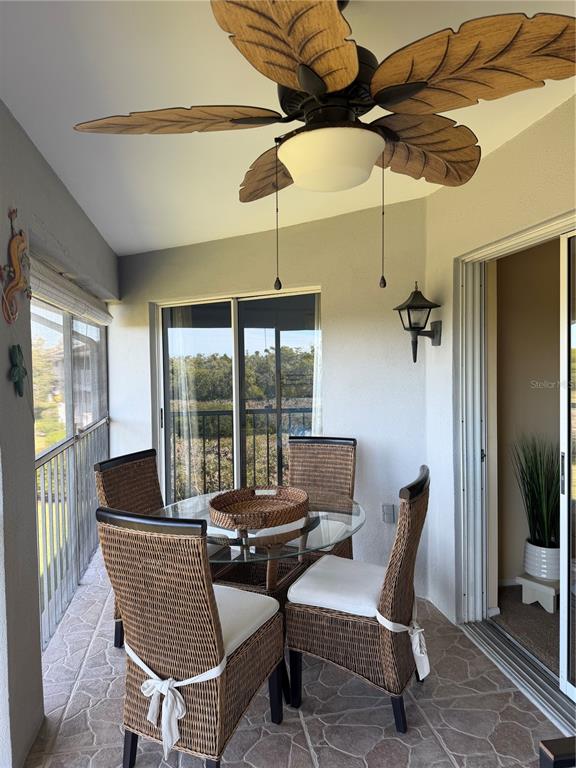 A covered balcony features a glass-top wicker dining set, a palm-leaf ceiling fan, and tile flooring — 708 ESTUARY DRIVE UNIT 708, BRADENTON, FL