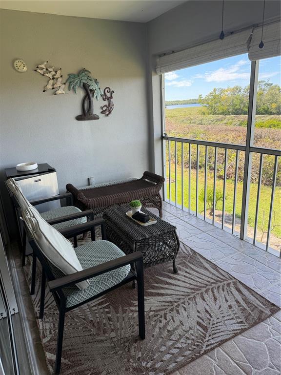 A screened-in porch features wicker furniture, a rug, and a view of a grassy landscape — 708 ESTUARY DRIVE UNIT 708, BRADENTON, FL