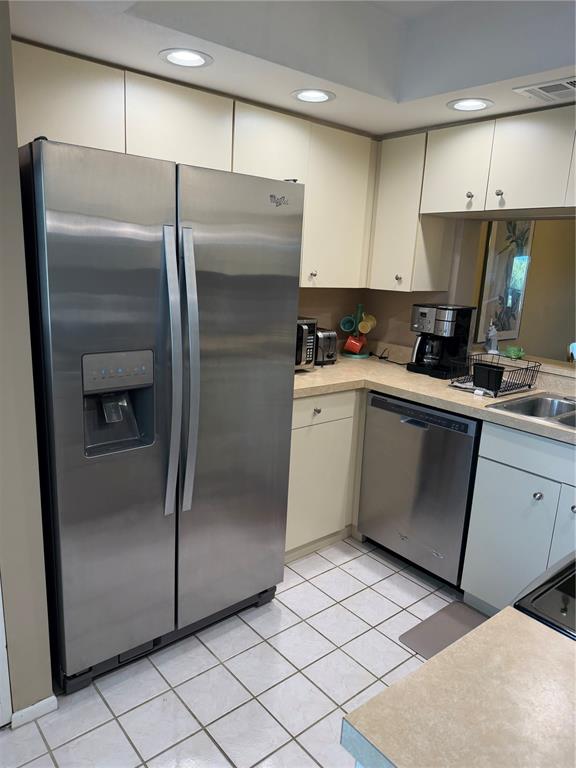 A kitchen features stainless steel appliances, light-colored cabinets, and white tile flooring — 708 ESTUARY DRIVE UNIT 708, BRADENTON, FL