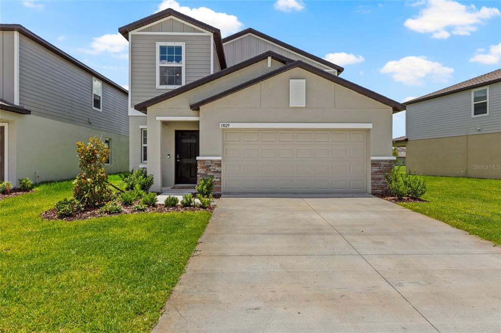 A two-story house with a beige stucco exterior, a two-car garage, and a concrete driveway — 13029 EMPRESS JEWEL TRAIL, PARRISH, FL