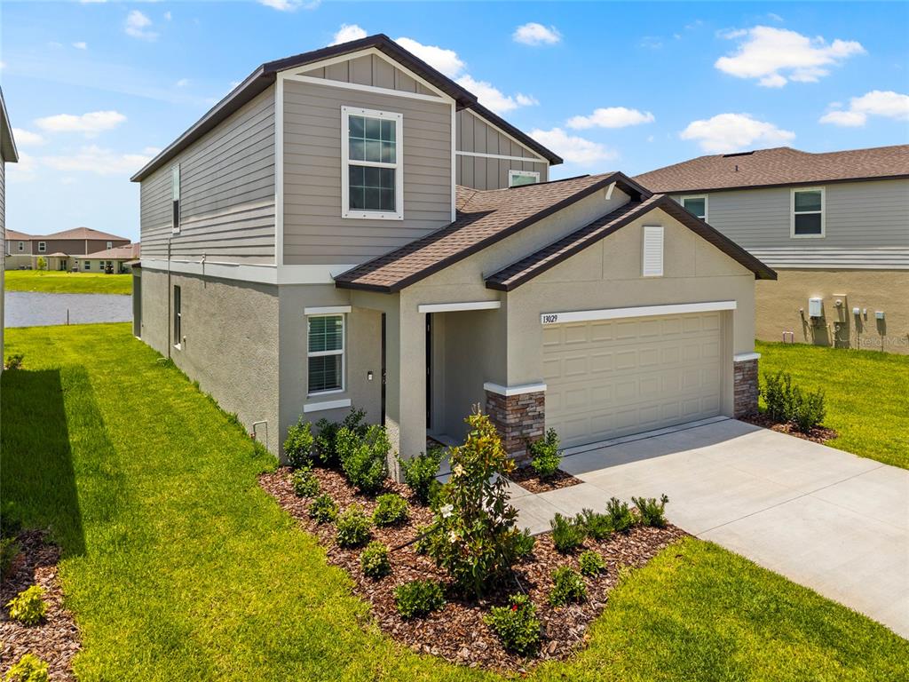 A two-story suburban house with a tan stucco and gray siding exterior and a garage — 13029 EMPRESS JEWEL TRAIL, PARRISH, FL