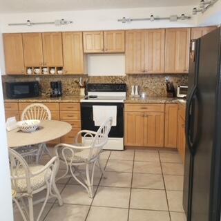 A kitchen features light wood cabinets, granite countertops, a black stove, and a small dining table — 11142 Green Lake Drive # 202, Boynton Beach FL 33437, BOYNTON BEACH, FL