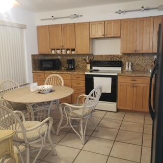 A kitchen with light wood cabinets, granite countertops, tile floors, and a round dining table — 11142 Green Lake Drive # 202, Boynton Beach FL 33437, BOYNTON BEACH, FL