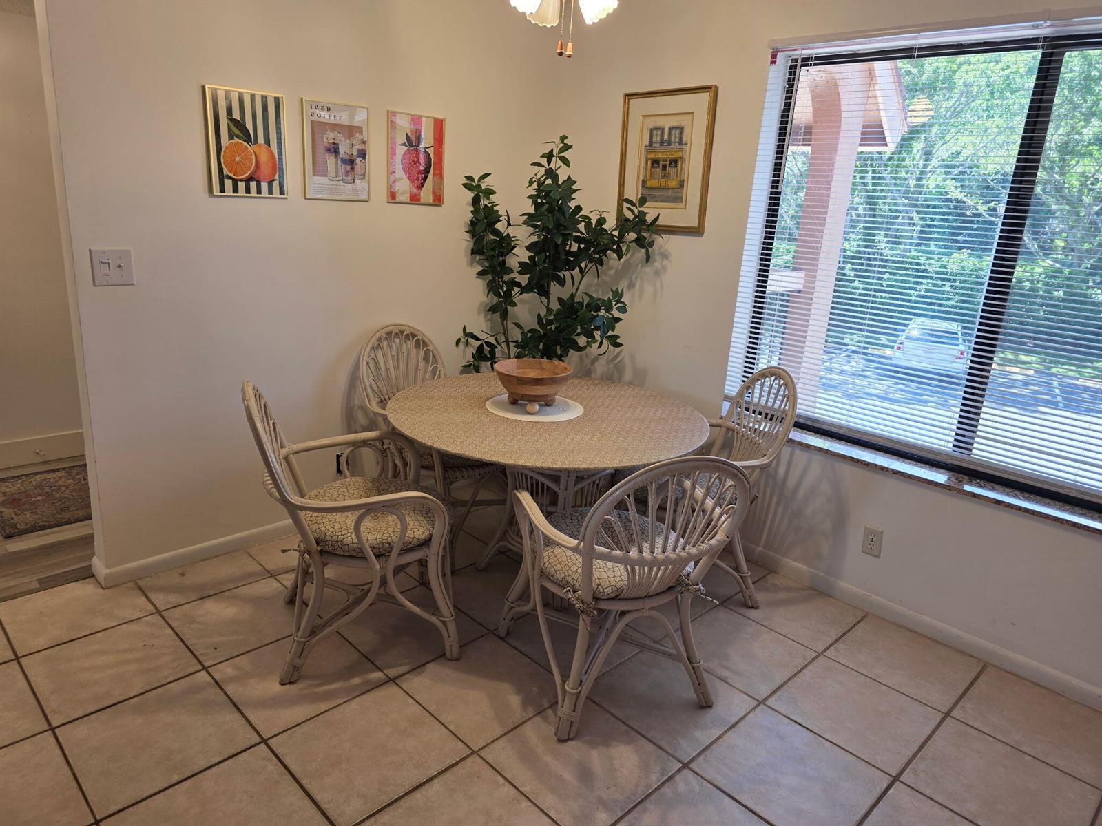 A dining area features a round wicker table with four matching chairs on tiled flooring — 11142 Green Lake Drive # 202, Boynton Beach FL 33437, BOYNTON BEACH, FL