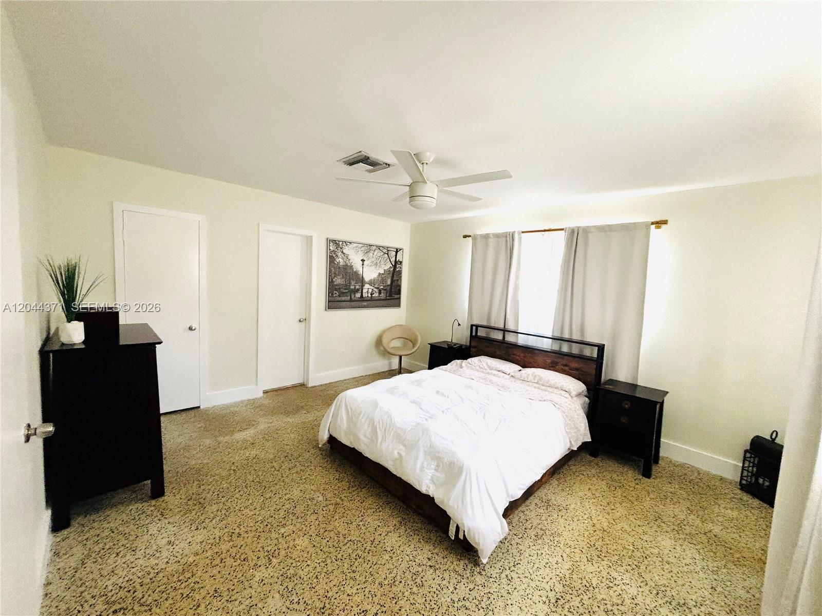 A bedroom features a bed, two nightstands, a dresser, carpeted flooring, and two closed doors — NORTH MIAMI BEACH, FL