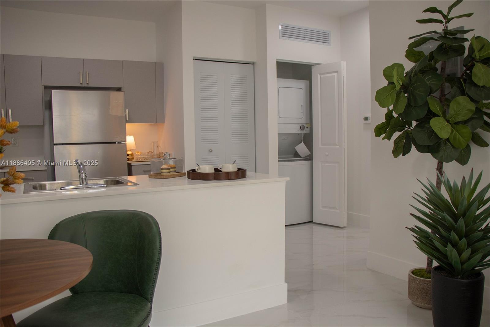 A kitchen with gray cabinets and stainless steel appliances features a laundry closet nearby — 1453 W 29th St # 307, Hialeah FL 33012, HIALEAH, FL