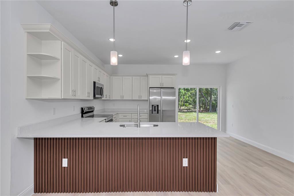 A modern kitchen features white cabinets, a slatted wood island, and stainless steel appliances — 6665 N DARLINGTON DRIVE, CITRUS SPRINGS, FL