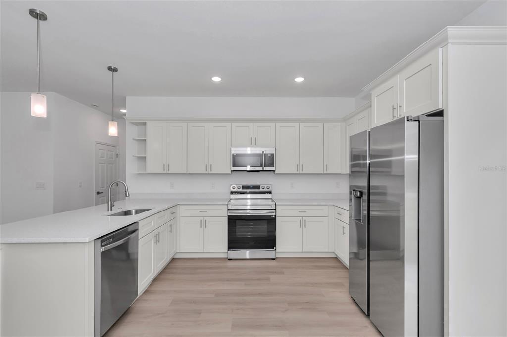 A modern kitchen features white cabinets, stainless steel appliances, and a large island with sink — 6665 N DARLINGTON DRIVE, CITRUS SPRINGS, FL