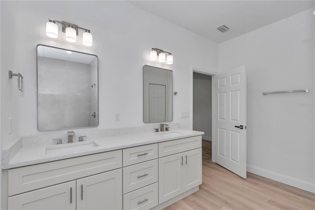 A bathroom features a double vanity with white cabinets, quartz countertops, and two rectangular mirrors — 6665 N DARLINGTON DRIVE, CITRUS SPRINGS, FL