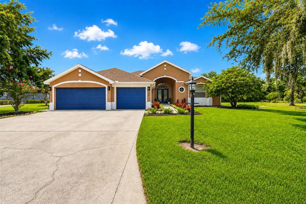 A single-story house with a tan stucco exterior, blue garage doors, and a concrete driveway — 2813 HAMPTON PLACE COURT, PLANT CITY, FL