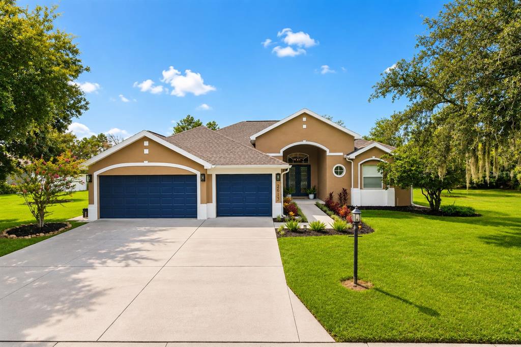 A single-story house with a tan exterior, blue garage doors, and a concrete driveway — 2813 HAMPTON PLACE COURT, PLANT CITY, FL
