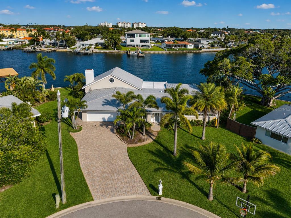 An aerial view shows a waterfront house with a paved driveway and palm trees — 1276 37TH AVENUE NE, ST PETERSBURG, FL