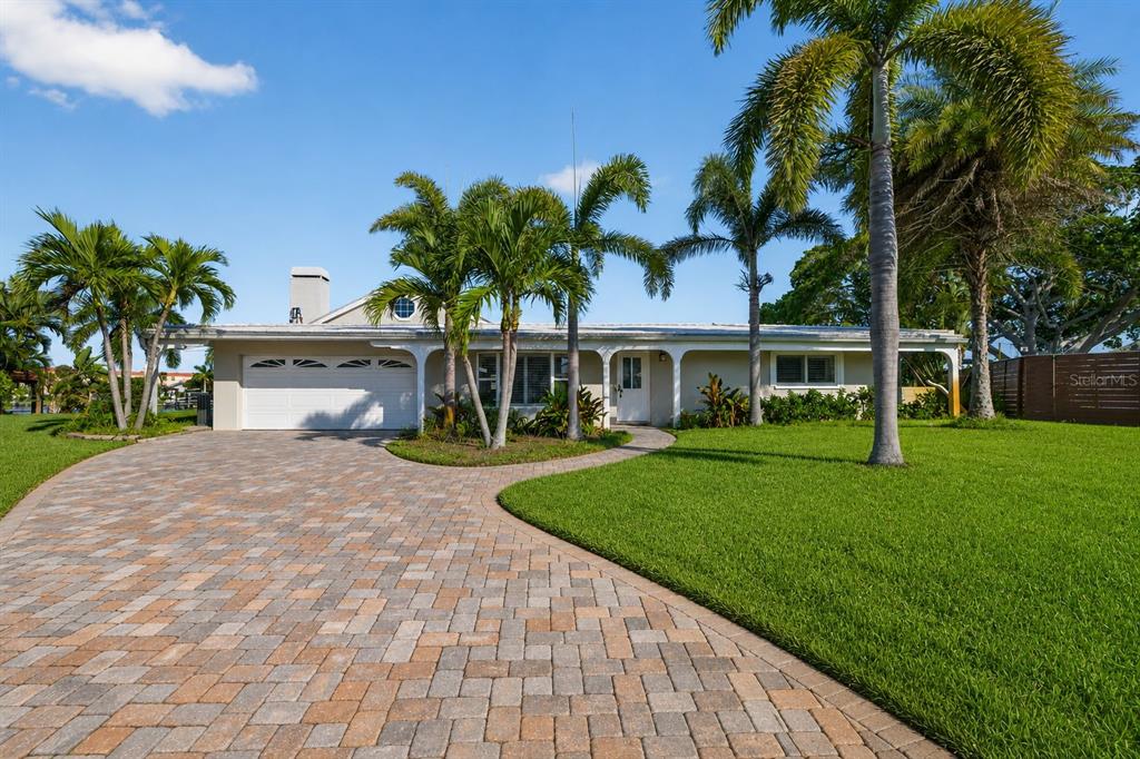 A single-story house with a paved driveway, palm trees, and a white garage door — 1276 37TH AVENUE NE, ST PETERSBURG, FL