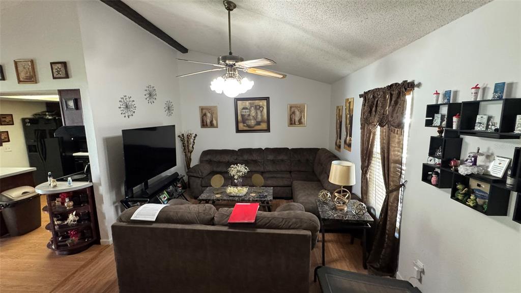 A living room features a brown sectional sofa, a television, and wall-mounted shelving — 4026 KILLIAN DR., ORLANDO, FL