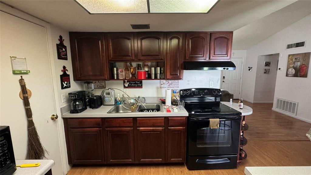 A kitchen features dark wood cabinets, black appliances, and a stainless steel sink — 4026 KILLIAN DR., ORLANDO, FL