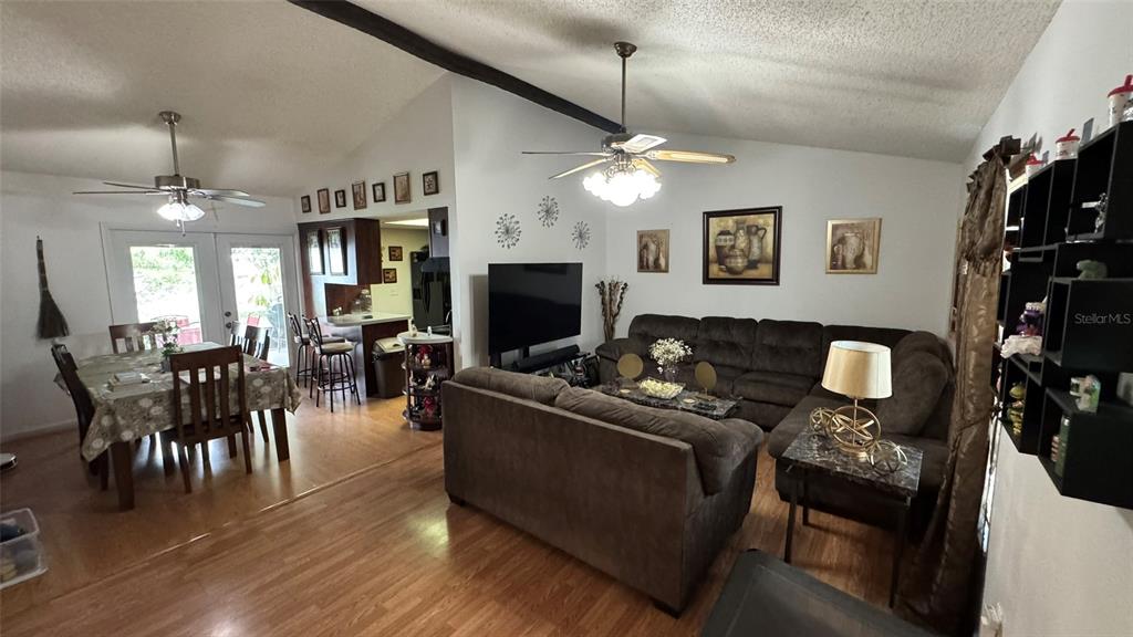 A living room and dining area feature wood-look flooring, vaulted ceilings, and dark brown furniture — 4026 KILLIAN DR., ORLANDO, FL