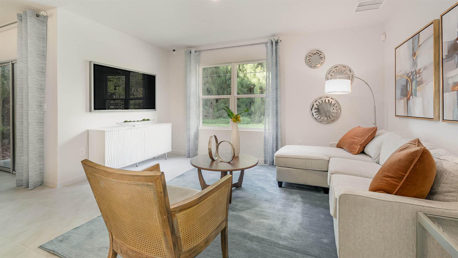 A living room features a sectional sofa, a wooden armchair, and a wall-mounted television — 866 NE 16th Avenue, Okeechobee FL 34972, OKEECHOBEE, FL