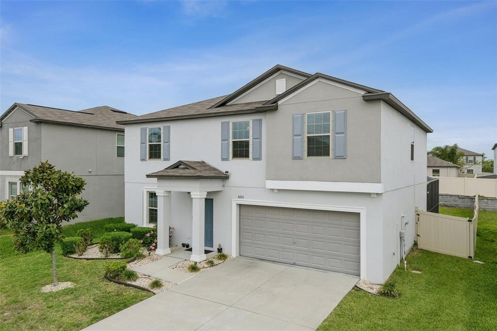 A two-story suburban house with a gray garage, light-colored stucco siding, and blue shutters — 4203 HANOVER DRIVE, NEW PORT RICHEY, FL