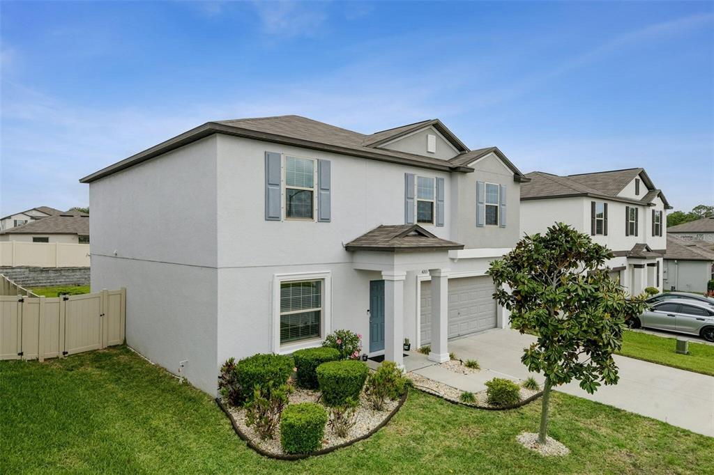 A two-story suburban house with light gray stucco, blue shutters, and a front garden bed — 4203 HANOVER DRIVE, NEW PORT RICHEY, FL