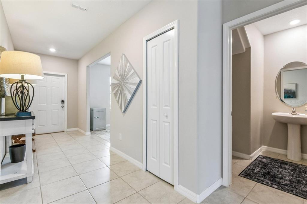 A bright entryway features tile flooring, a white closet door, and an adjacent half bathroom — 4203 HANOVER DRIVE, NEW PORT RICHEY, FL
