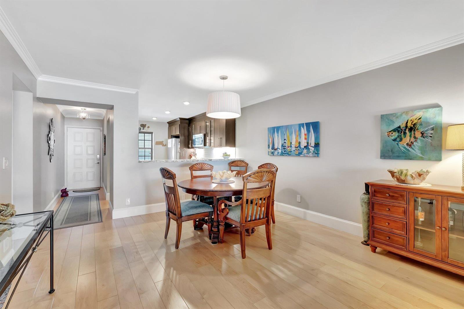 A dining area with a round wooden table, four chairs, and a wooden sideboard — 701 Avenue L, Delray Beach FL 33483, DELRAY BEACH, FL