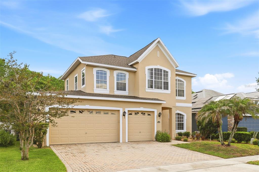 A two-story house with a tan stucco exterior, a two-car garage, and a paved driveway — 16368 TUDOR GROVE DRIVE, ORLANDO, FL