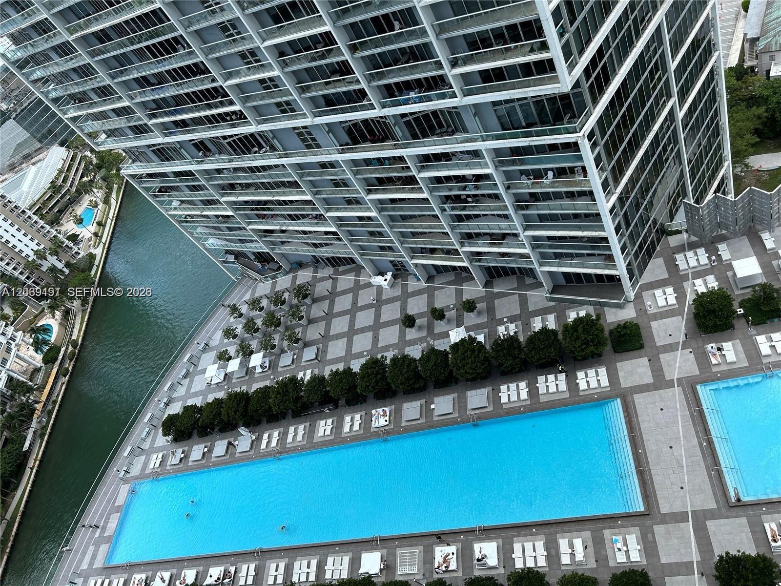 An aerial view shows a large swimming pool and patio area beside a tall building — 475 Brickell Ave # 3113, Miami FL 33131, MIAMI, FL