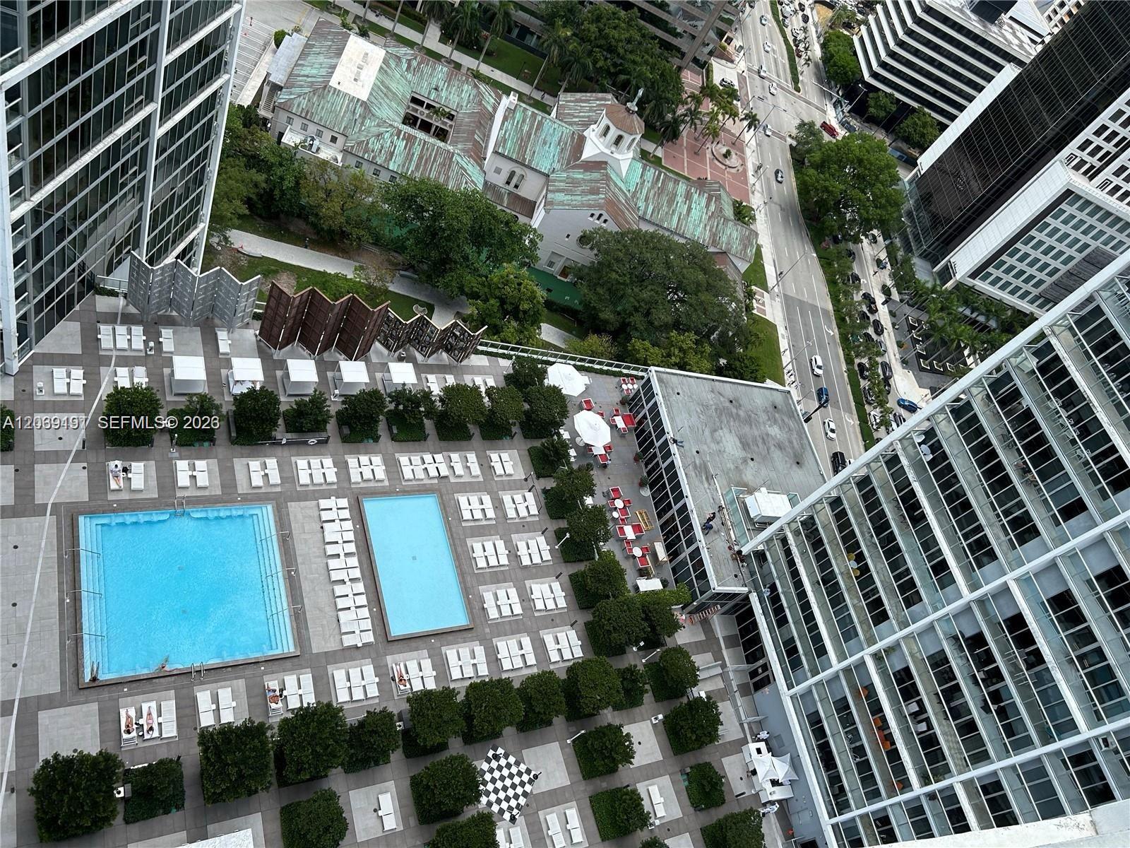 An aerial view shows a pool deck with two swimming pools surrounded by lounge chairs — 475 Brickell Ave # 3113, Miami FL 33131, MIAMI, FL