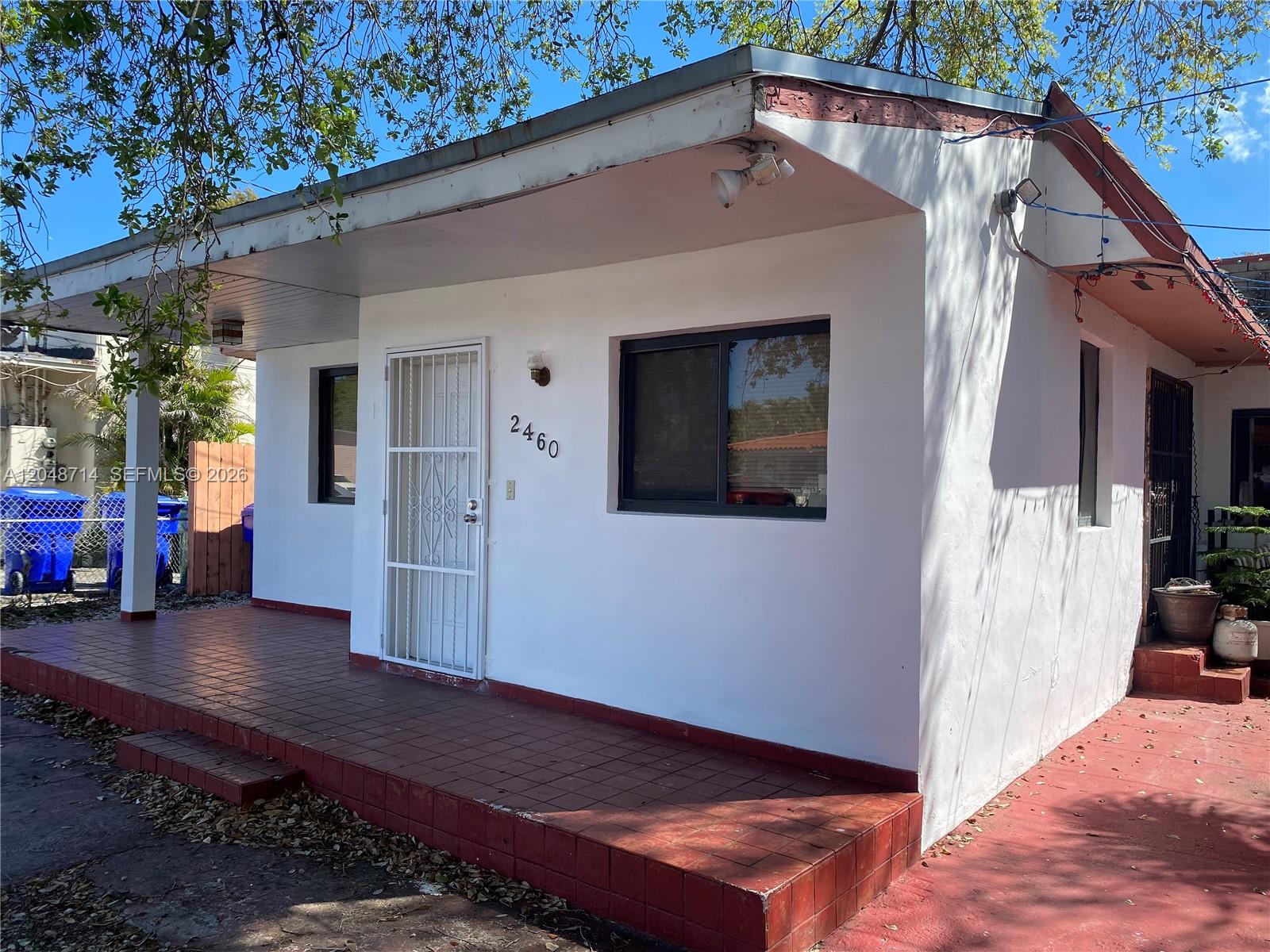 A small, white, single-story house features a tiled front porch and a security door — 2460 NW 15th St # 4, Miami FL 33125, MIAMI, FL