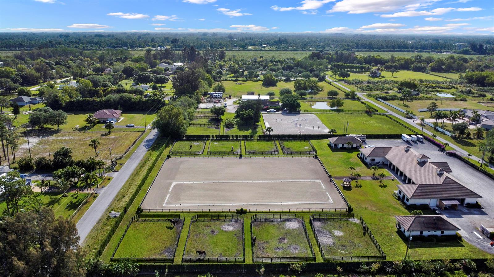 An aerial view of an equestrian property featuring a large riding arena and horse paddocks — 16575 Van Gogh Road, Wellington FL 33414, WELLINGTON, FL