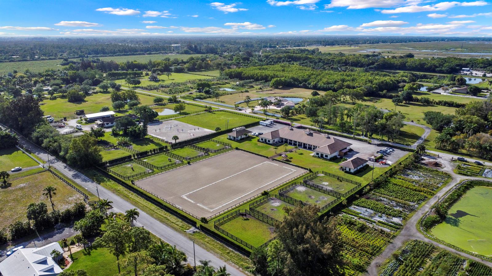An aerial view shows a horse farm with riding arenas, stables, and fenced pastures — 16575 Van Gogh Road, Wellington FL 33414, WELLINGTON, FL