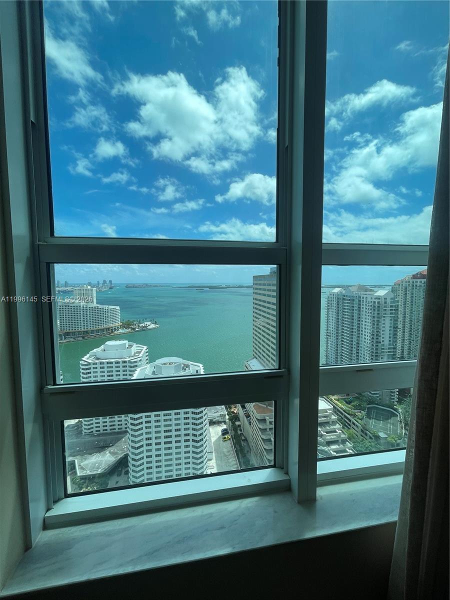A high-rise window view overlooks a bay, surrounding skyscrapers, and a tennis court below — 951 Brickell Ave # 3506, Miami FL 33131, MIAMI, FL