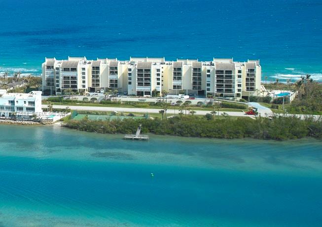 An aerial view shows a large multi-story apartment complex situated between the ocean and a bay — 19670 Beach Rd # B323, Tequesta FL 33469, TEQUESTA, FL