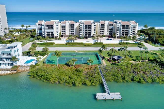 An aerial view shows a beachfront condominium complex with a tennis court and a private dock — 19670 Beach Rd # B323, Tequesta FL 33469, TEQUESTA, FL