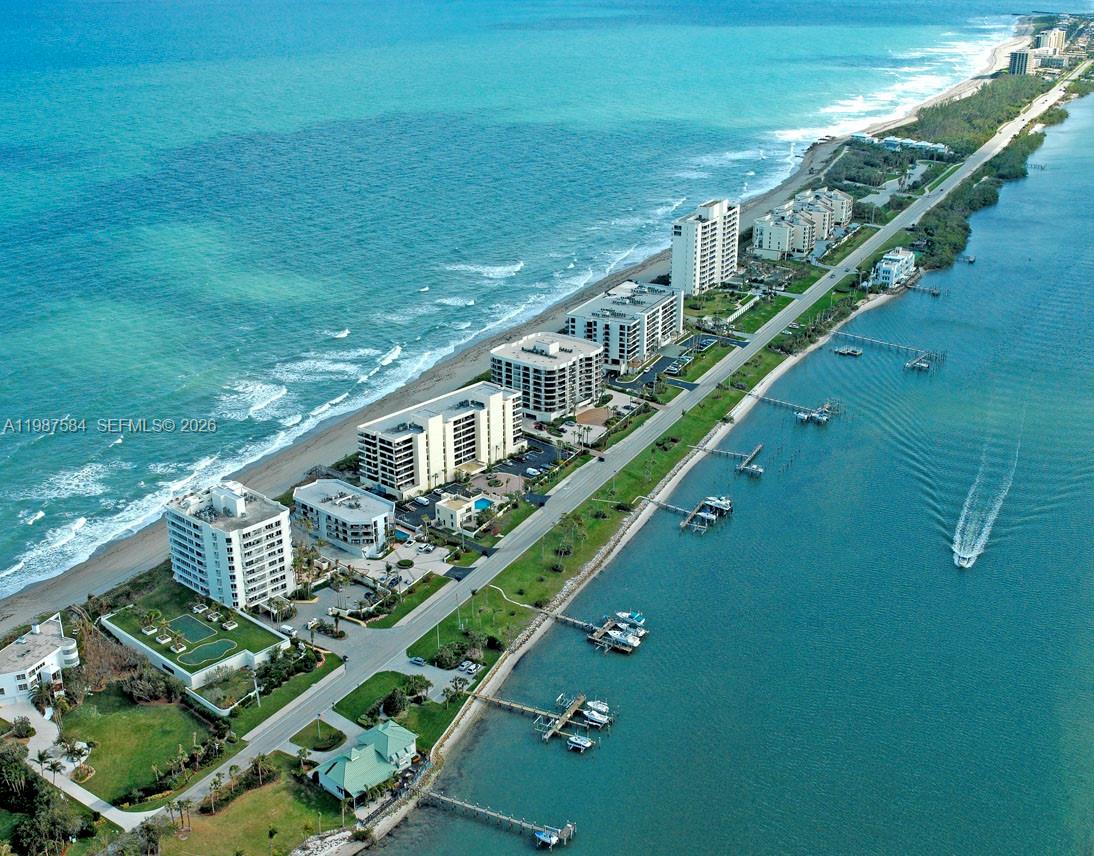 An aerial view shows a narrow coastal strip with residential buildings between the ocean and bay — 19670 Beach Rd # B323, Tequesta FL 33469, TEQUESTA, FL