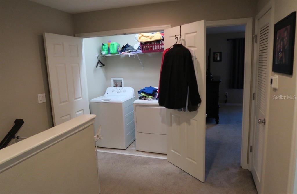 A laundry closet with a washer and dryer is located in a carpeted hallway — 7024 WOODCHASE GLEN DRIVE, RIVERVIEW, FL