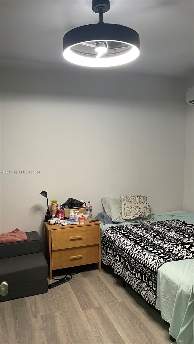 A bedroom features a light wood nightstand, a bed with patterned bedding, and a ceiling fan — 1043 NW 2nd St # 2, Miami FL 33128, MIAMI, FL