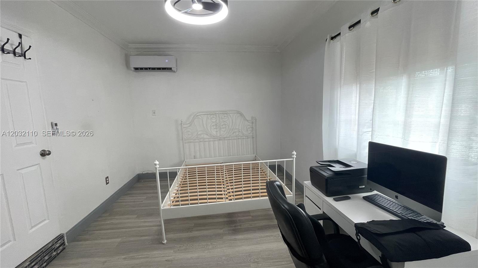 A bedroom features a white metal bed frame, a desk with a computer, and wood-look flooring — 1043 NW 2nd St # 2, Miami FL 33128, MIAMI, FL