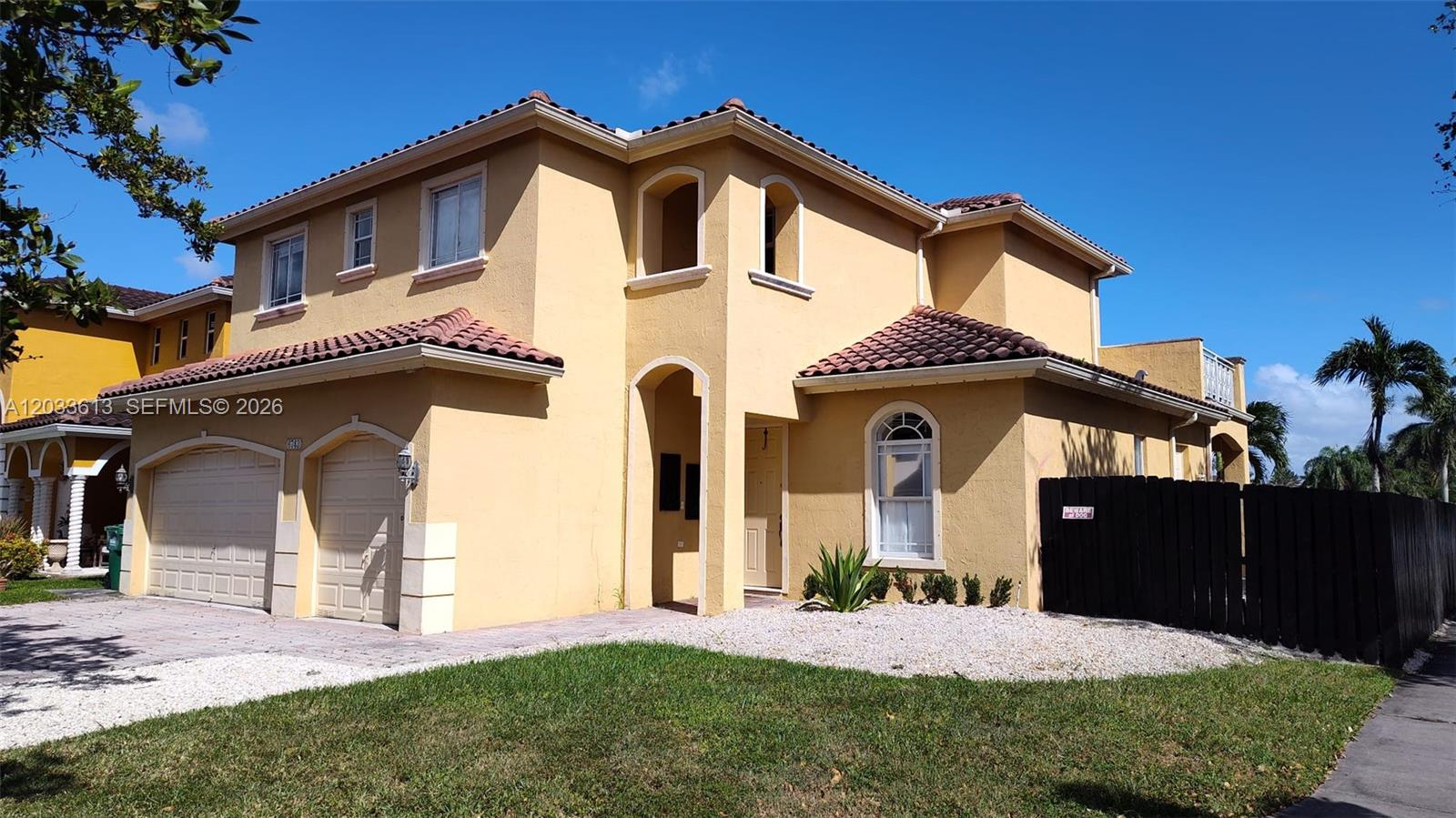 A two-story yellow stucco house features a two-car garage, arched entryway, and tile roof — 6743 SW 163rd Pl, Miami FL 33193, MIAMI, FL