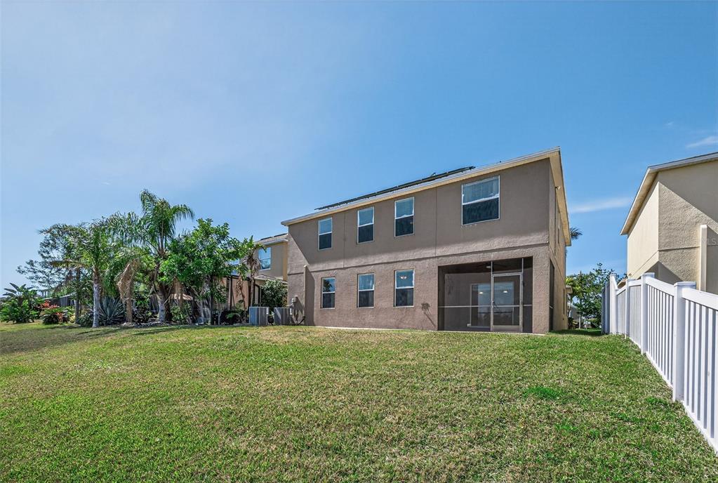 The rear exterior of a two-story tan house features a screened-in patio and lawn — 521 VISTA RIDGE DRIVE, RUSKIN, FL