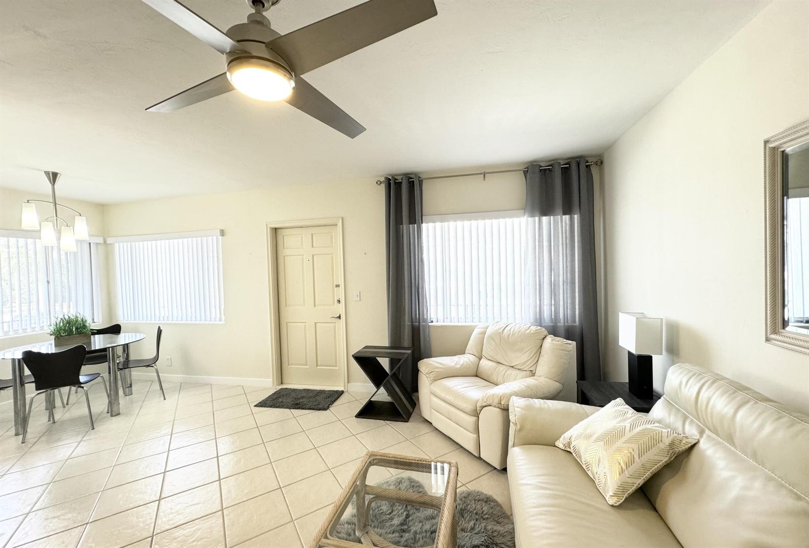A living and dining area features tile floors, a ceiling fan, and white leather furniture — 2880 Lake Osborne Drive # 205, FL 33461, FL