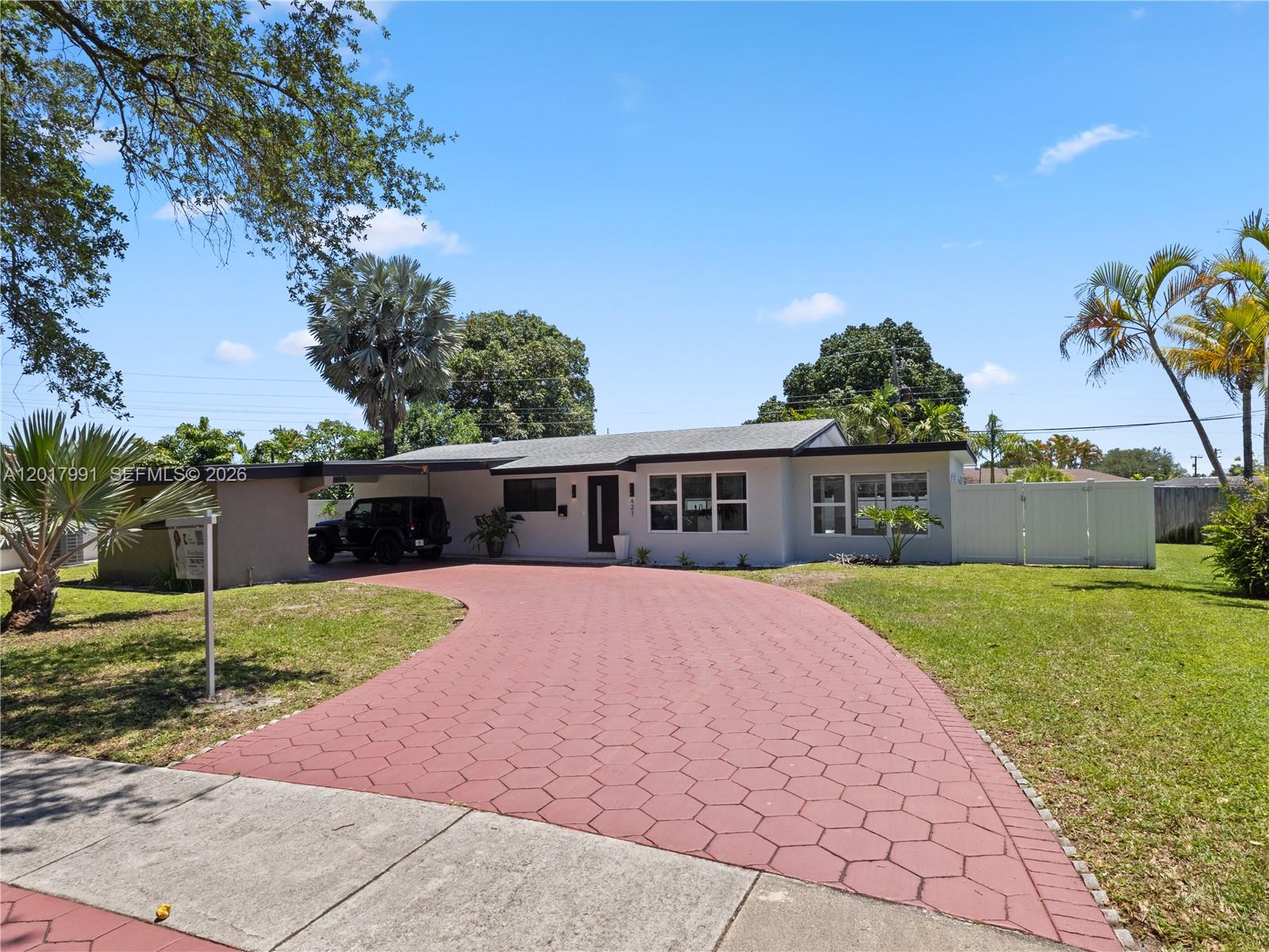 A single-story house with a red paver driveway and a carport under a blue sky — 421 S 56th Ter, Hollywood FL 33023, HOLLYWOOD, FL