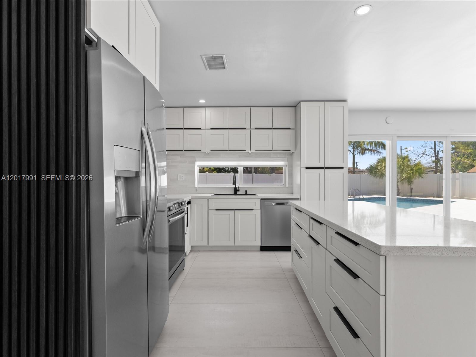 A modern kitchen features white cabinetry, stainless steel appliances, a large island, and pool views — 421 S 56th Ter, Hollywood FL 33023, HOLLYWOOD, FL