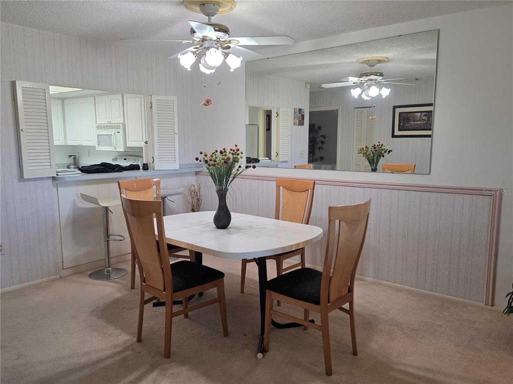 A dining area features a white table, four wooden chairs, and a large wall mirror — 3500 EL CONQUISTADOR PARKWAY UNIT 260, BRADENTON, FL
