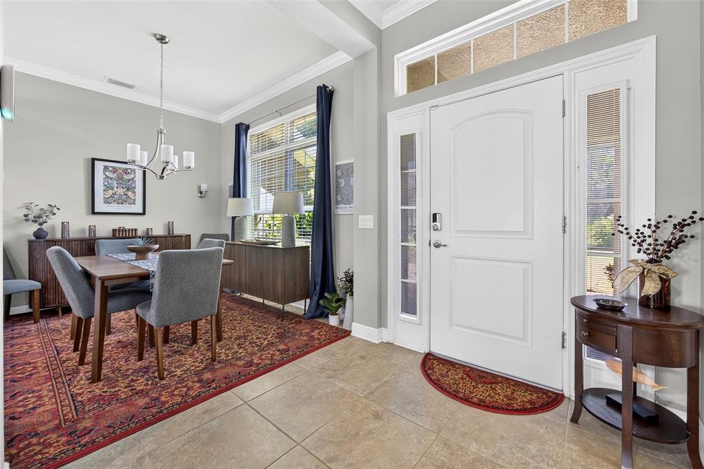 A dining area with a rug and table sits beside a white front entry door — 1667 MADISON AVENUE, NORTH PORT, FL