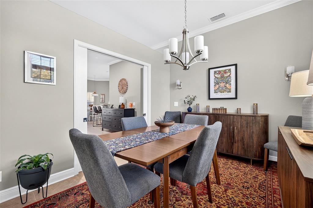 A dining room features a wooden table, grey upholstered chairs, a sideboard, and a chandelier — 1667 MADISON AVENUE, NORTH PORT, FL