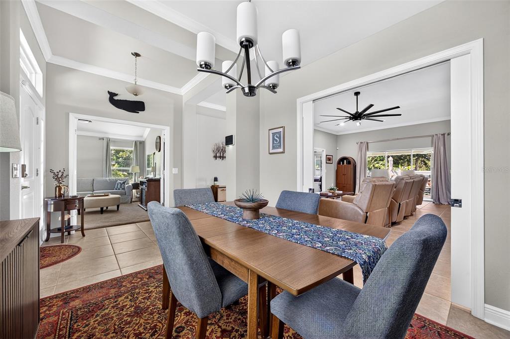 A dining room with a wooden table, blue chairs, and a chandelier, opening into adjacent rooms — 1667 MADISON AVENUE, NORTH PORT, FL